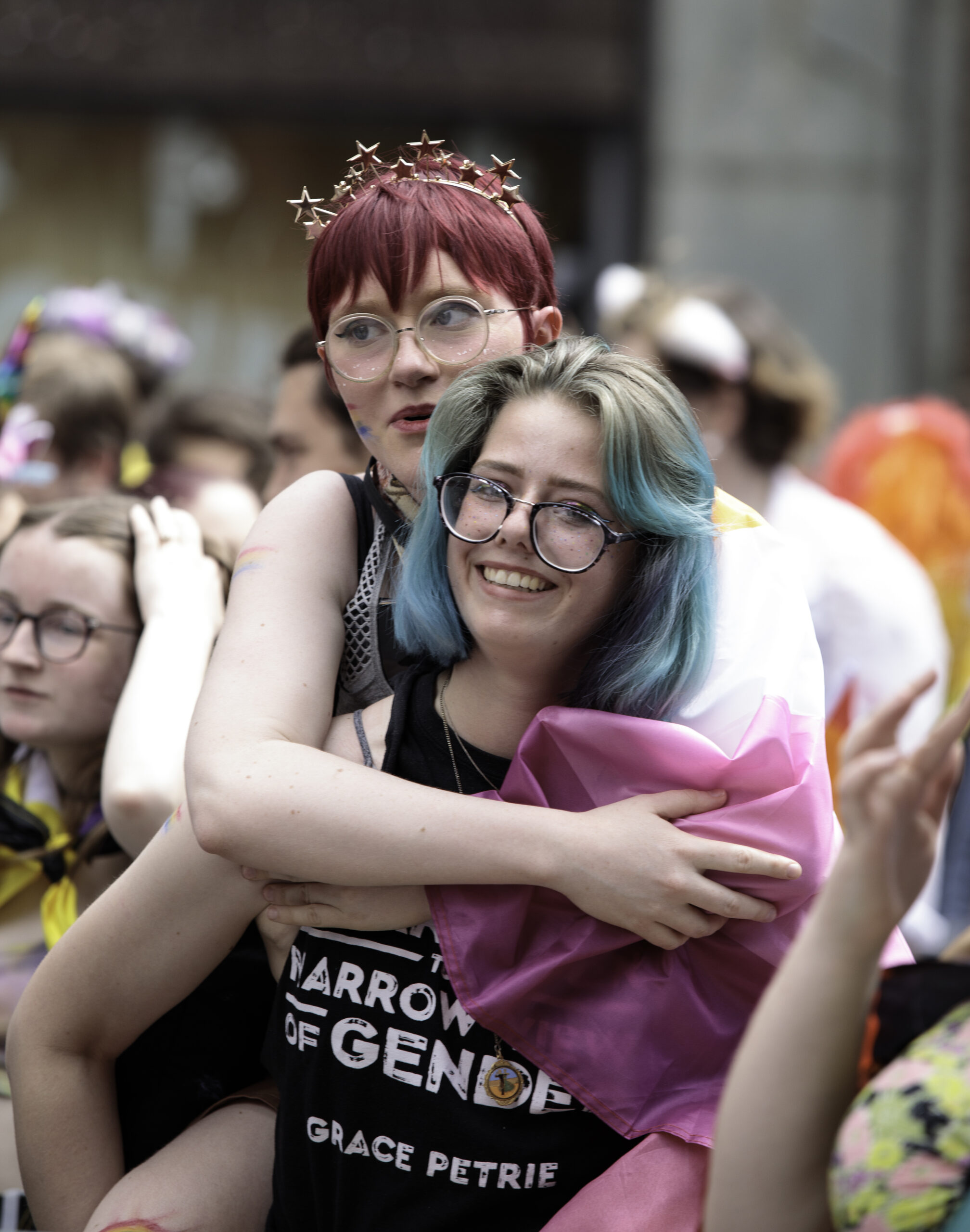 Two young women, one is giving the other a piggy back. The photo was taken at Exeter pride. 